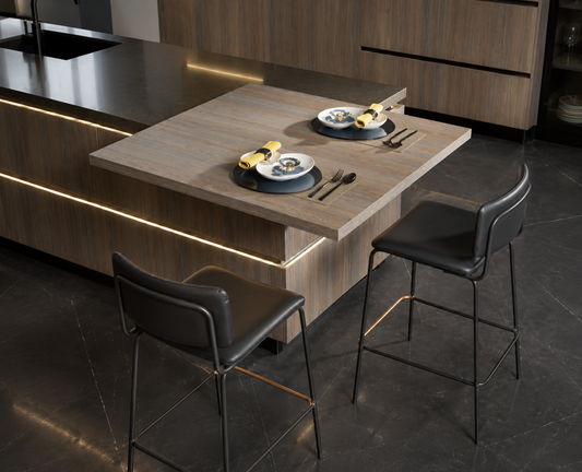 A modern kitchen island with a light wood tabletop and dark wood cabinetry, shown with two black bar stools and place settings on the table.
