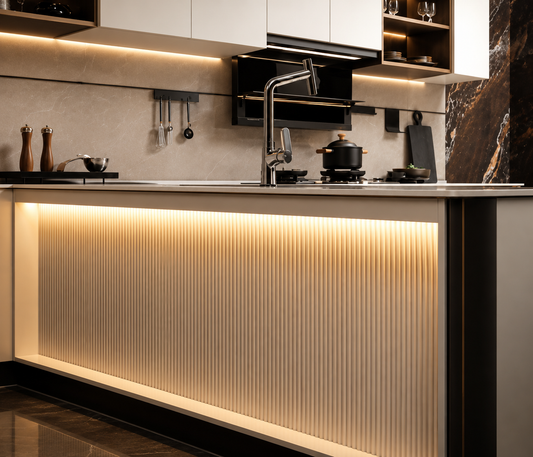 Modern kitchen island with a ribbed beige front panel and warm under-cabinet lighting, set in a contemporary kitchen with dark cabinetry and cookware.