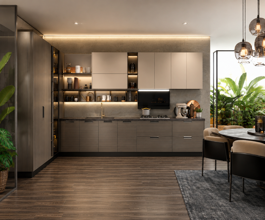 A modern kitchen cabinetry set with matte taupe-gray doors and dark gray countertops, shown installed in a styled interior with wood flooring, dining chairs, pendant lights, and green plants.