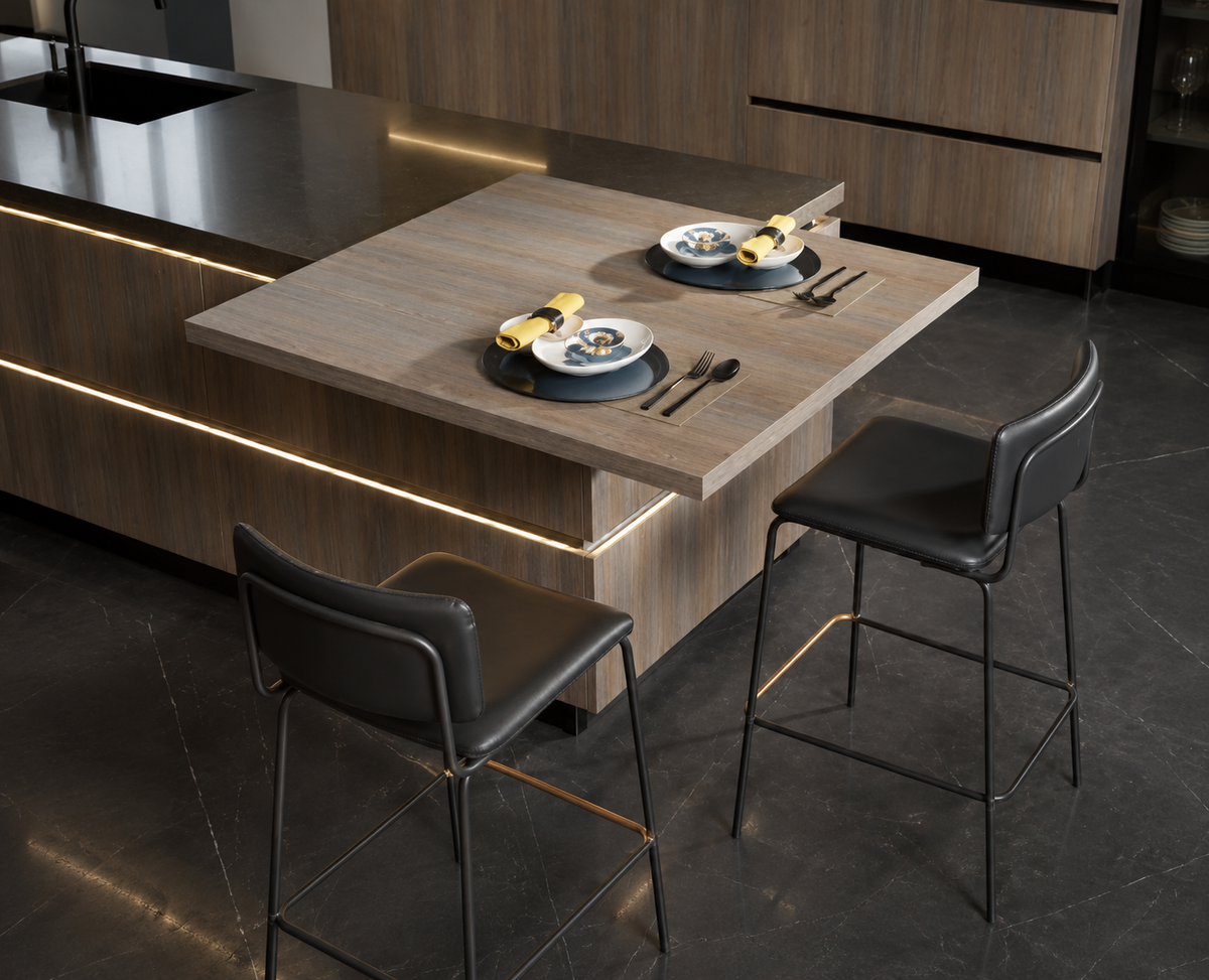 A modern kitchen island with a light wood tabletop and dark wood cabinetry, shown with two black bar stools and place settings on the table.