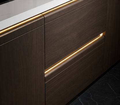 Close-up of modern dark wood kitchen cabinetry with a white countertop and warm LED under-light striping.