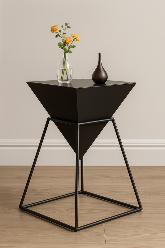 Black geometric side table with a vase and flowers on a wooden floor.