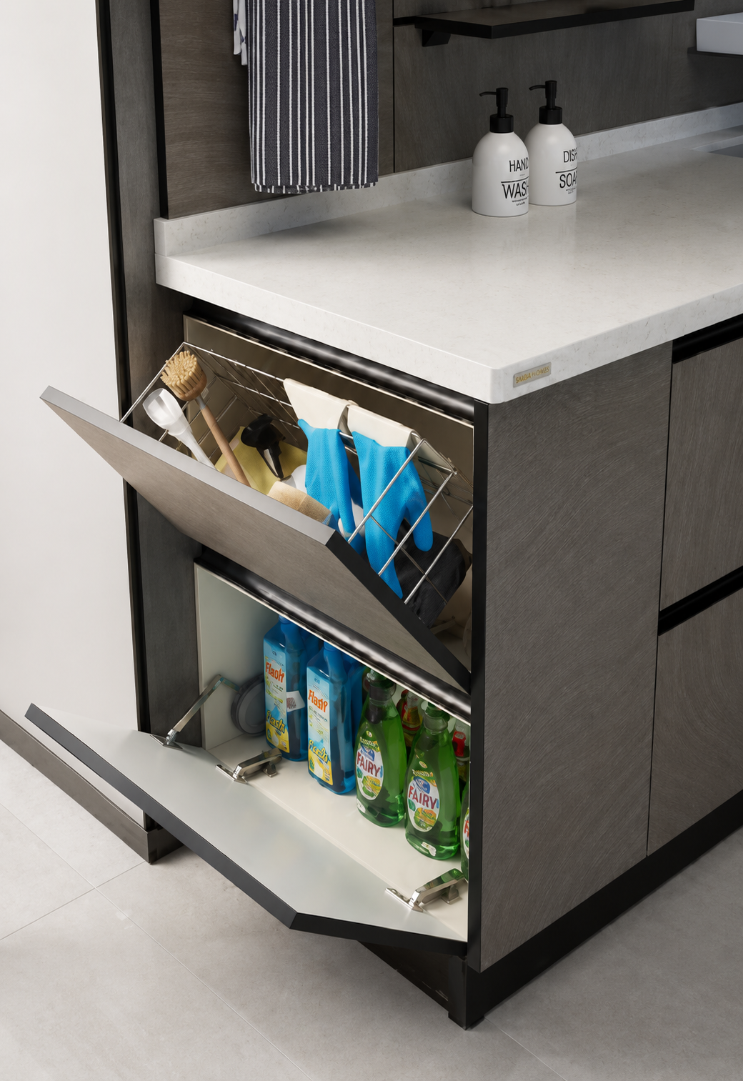 A modern kitchen or bathroom cabinet with a white countertop and dark gray wood-grain doors, shown with two pull-out lower cabinets open to reveal cleaning supplies and bottles inside.
