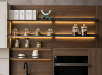 Modern kitchen cabinetry with dark wood grain, open shelves, warm under-shelf lighting, glass canisters, books, cups, and a built-in black appliance.