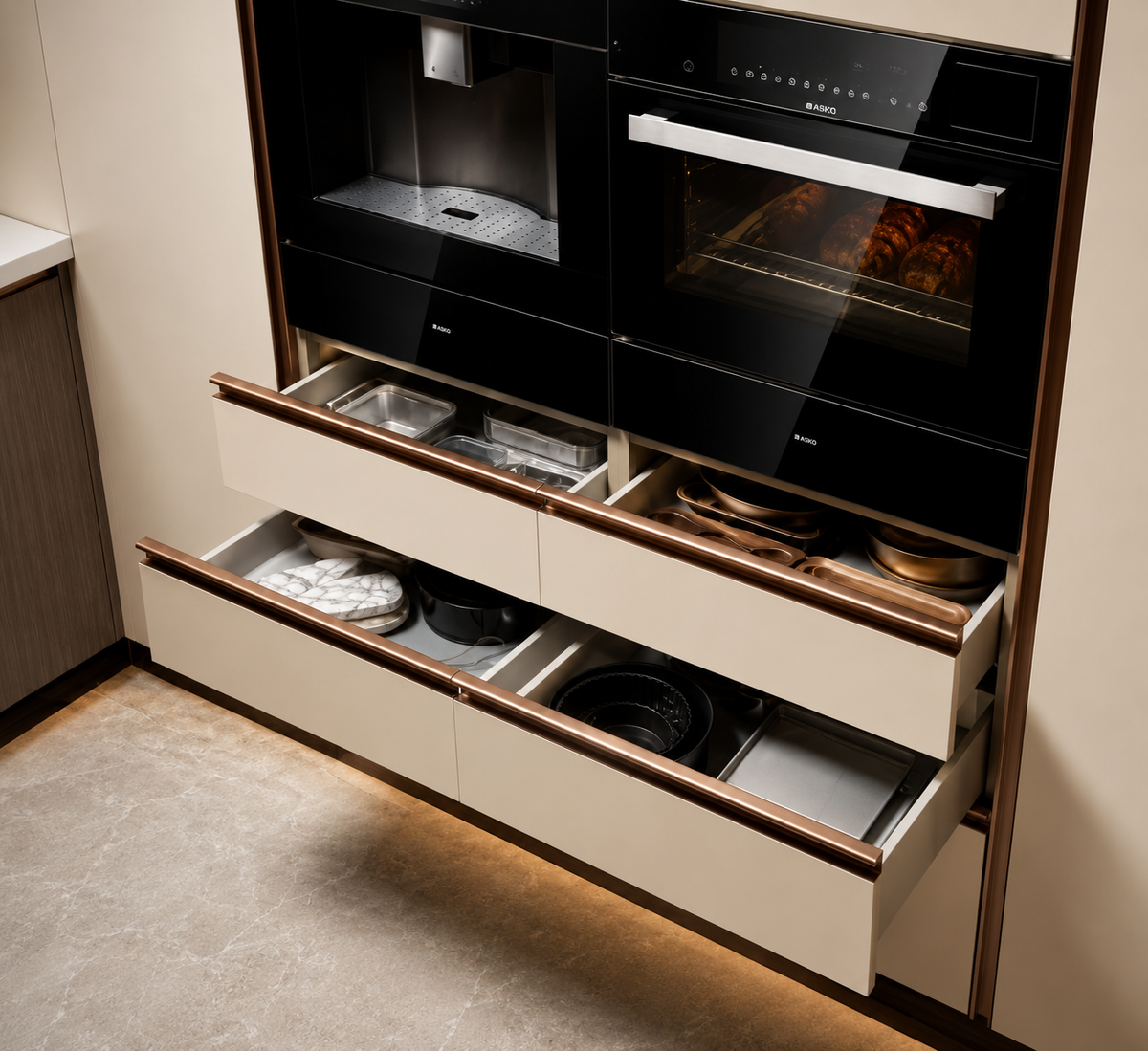 A modern built-in kitchen cabinet system with two black glass built-in ovens on the upper section and three cream-colored drawers with copper-toned trim on the lower section, some of which are open to reveal cookware and dishes inside.