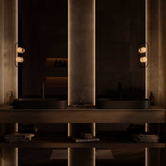 Dark luxury bathroom with double matte black basins, warm backlit wall panels, wood open-shelf vanity, and ambient pendant lighting – SAIBA Homes.