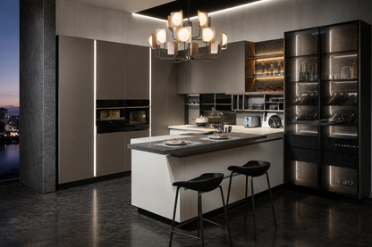 A luxury modern kitchen interior featuring a central white island with a dark countertop, two black bar stools, sleek dark cabinetry with vertical LED light strips, glass-front wine storage, and a multi-light chandelier overhead.
