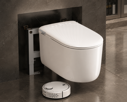 A white wall-mounted smart toilet with a matching lid, shown installed against a dark tiled wall in a bathroom setting, with a small white robotic cleaner on the floor below.