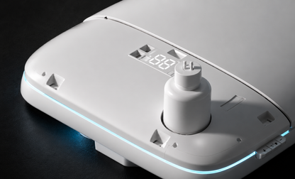 A close-up of a white electronic device with a central cylindrical knob, a small digital display reading 18:18, and a thin blue LED light strip along the edge, set against a dark background.