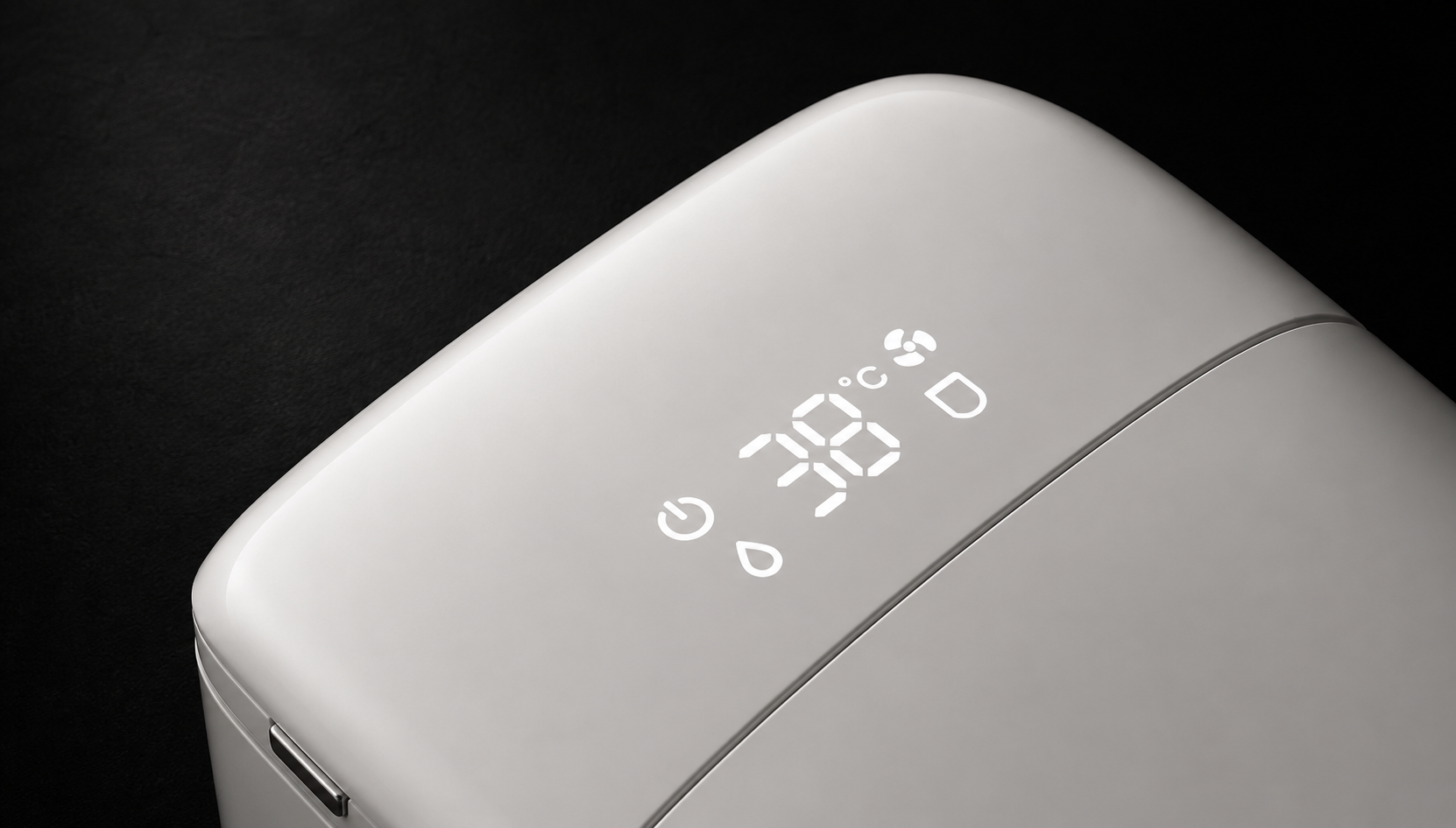 Close-up of a white electronic device with a glossy finish, featuring a digital LED display showing 38 degrees Celsius and status icons, set against a dark background.