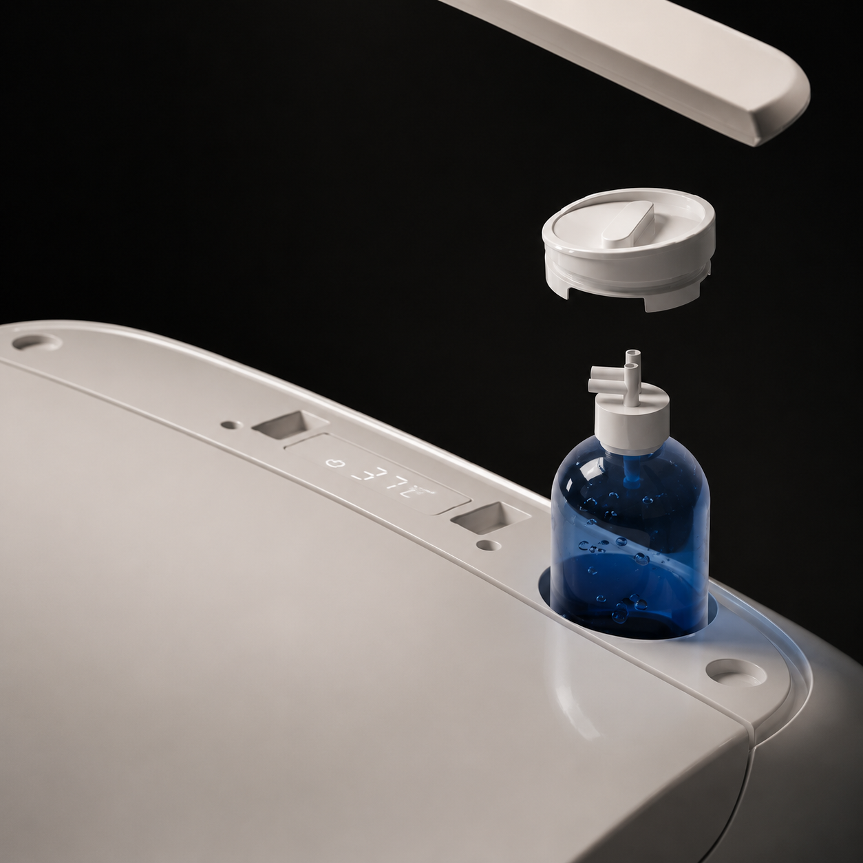Close-up of a white toilet paper dispenser with a blue bottle and white cap inserted into a slot, shown against a black background.