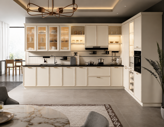 A modern kitchen cabinet set in an off-white/cream finish with black countertops and integrated appliances, shown in a styled interior room with a dining area and rug.