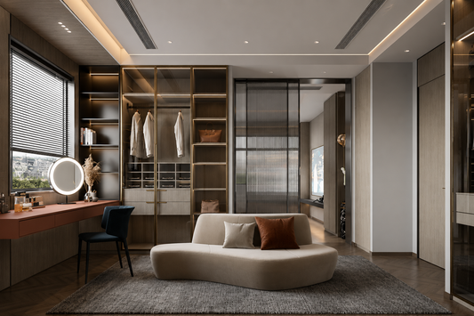 A modern home office or dressing room interior with a curved cream sofa, built-in wood shelving, a desk with a blue chair, and a large gray rug in a well-lit contemporary room.