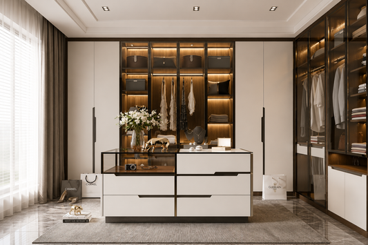 A modern walk-in closet room featuring a large white and black central storage cabinet with drawers, glass doors, and illuminated shelving. The room has matching built-in wardrobes on both sides with hanging garments, a gray rug, and soft natural light from a window with sheer curtains.